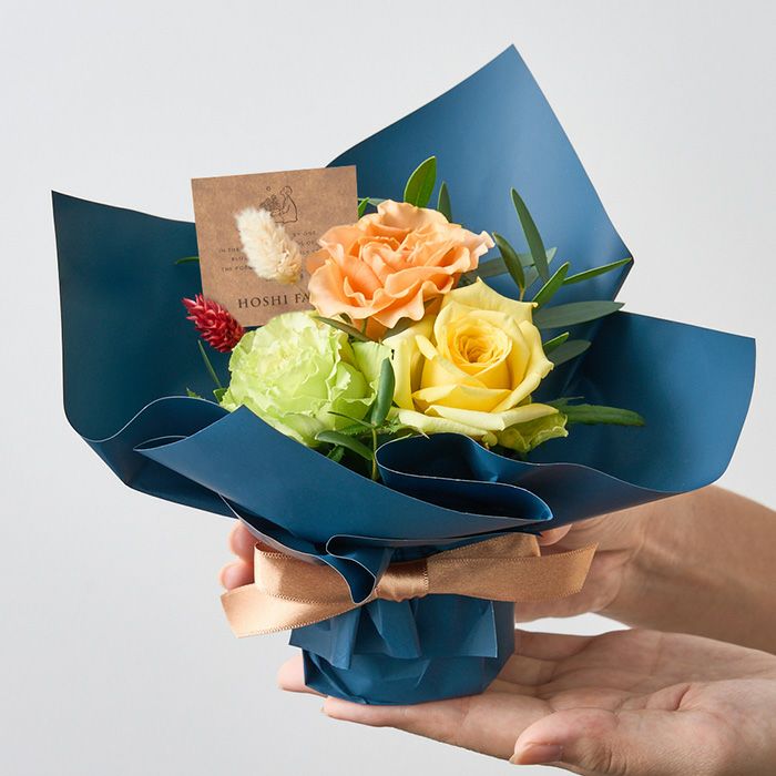 手にのるサイズの黄色などの明るい薔薇のミニアレンジメント